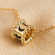 Close Up of Moon Phase Enamel Pendant Necklace in Gold Pendant on Beige Fabric 