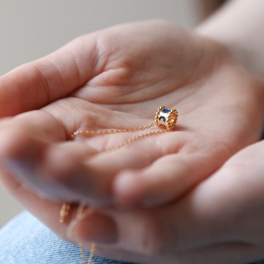 Model Holding Moon Phase Enamel Pendant Necklace in Gold in Palm of Hand