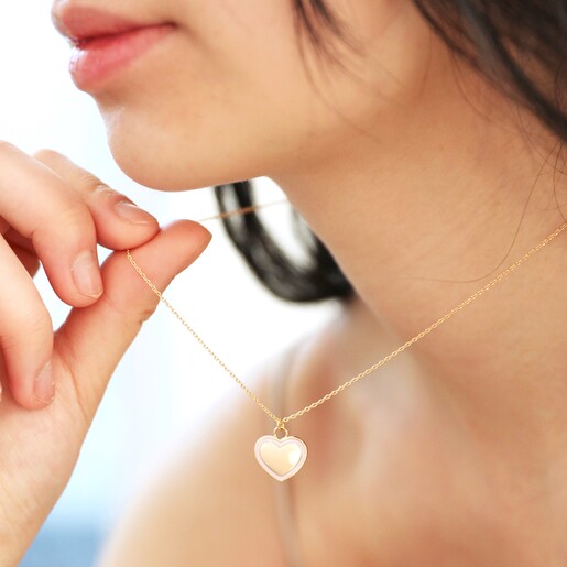 Model Wearing and Holding Pink Enamel Heart Pendant Necklace in Gold