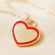 Red Enamel Heart Pendant Necklace in Gold on Fabric Close Up