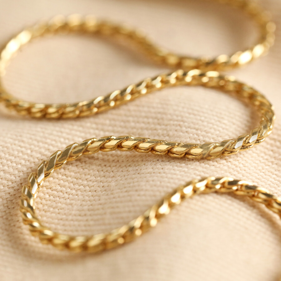 Woven Chain Necklace in Gold laid on top of neutral coloured material