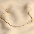 Rope Chain Necklace in Gold Laid Out on Neutral Coloured Fabric