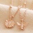 Close Up of Set of 2 Daisy and Bee Necklaces in Rose Gold on Fabric