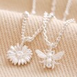 Close Up of Set of 2 Daisy and Bee Necklaces in Silver on Beige Fabric