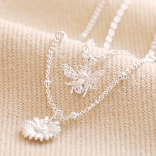Set of 2 Daisy and Bee Necklaces in Silver Layered on Beige Fabric