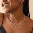 Model Smiling Wearing Tiny Pearl Initial Charm Necklace in Silver Layered with Other Necklaces