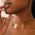 Close Up of Model Wearing Wildflower Envelope Locket Pendant Necklace in Gold Holding Chain in Hand