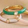 Green Enamel Crystal Ring in Gold with Pink Ring and White Ring on Beige Material