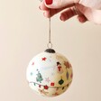 Model Holding the Hand-Painted Festive Christmas Bauble in front of Neutral Background