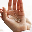 Organic Hoops Pendant Necklace in Silver Held in Hand by Model with Cream Backdrop