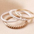 Set of 4 Silver and Gold Stacking Rings Layered on Each Other on a Beige Fabric