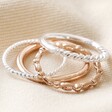 Set of 4 Silver and Rose Gold Stacking Rings Stacked on Top of Each Other on Beige Fabric