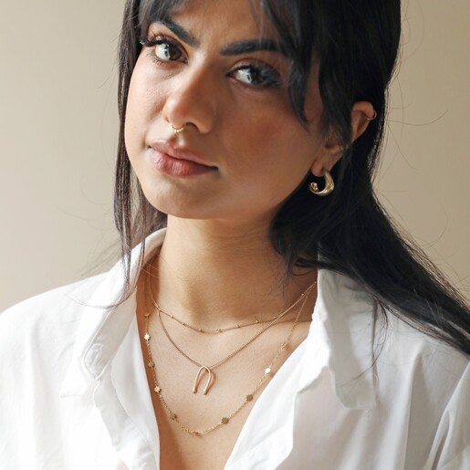 Model Wearing Slim Hug Hands Pendant Necklace in Gold Layered with Other Necklaces