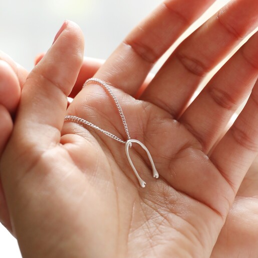 Model Holding Slim Hug Hands Pendant Necklace in Silver