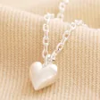 Close Up of Pendant on Tiny Heart Pendant Necklace in Silver on Natural Coloured Fabric