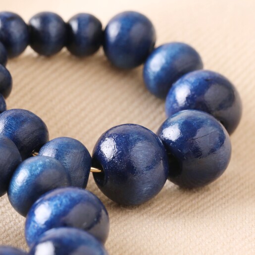 Close Up of Wooden Bead Drop Earrings in Navy on Natural Coloured Fabric