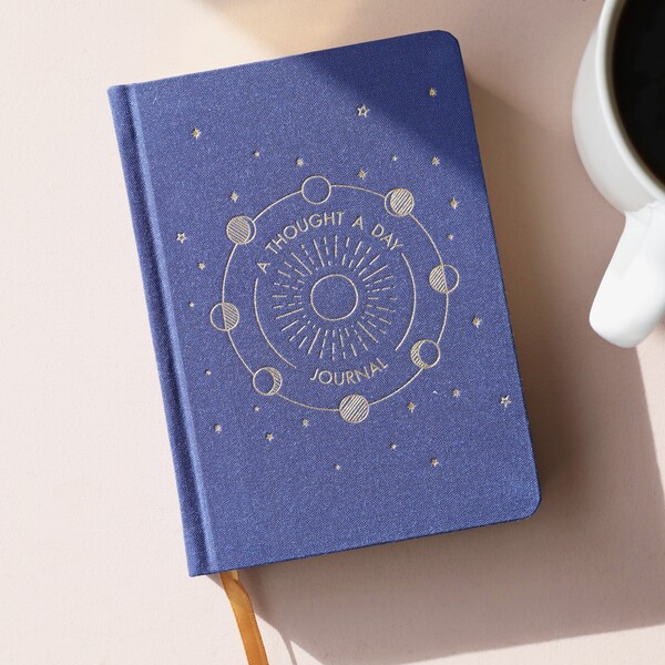 Navy Five Year Thought a Day Journal on top of beige backdrop with mug next to it