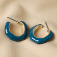 Big Metal London Blue Enamel Irregular Hoop Earrings in Gold on Beige Coloured Fabric