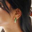 Close Up of Model Wearing Big Metal London Engraved Edge Green Enamel Hoop Earrings in Gold