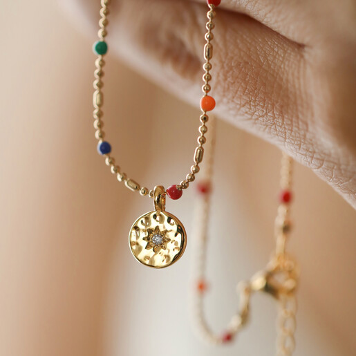 Model Holding Estella Bartlett Crystal Rainbow Pendant Necklace in Gold in Hand