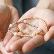 Model Holding Estella Bartlett Pack of 2 Gold & Multicolour Beaded Bracelets