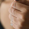 Model Holding Estella Bartlett North Star Pendant Necklace in Silver in Hand