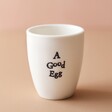 East of India Good Egg Porcelain Egg Cup Empty Against Pink Background