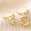 Crescent Moon & Star Charm Huggie Hoop Earrings in Gold on Beige Fabric