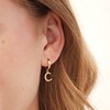 Close Up of Model Wearing Crescent Moon Charm Huggie in Gold