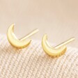 Tiny Crescent Moon Stud Earrings in Gold on Neutral Fabric