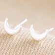 Tiny Crescent Moon Stud Earrings in Silver on Neutral Fabric