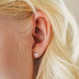 Close Up of Model Wearing Tiny Crystal Heart Stud Earrings in Silver