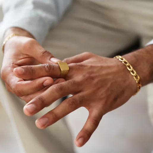 Model Wearing Men's Brushed Gold Stainless Steel Signet Ring And Gold Chain Bracelet