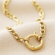 Gold Stainless Steel Figaro Chain Necklace Against Cream Fabric