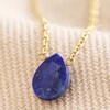 Close Up Semi-Precious Lapis Lazuli Stone Teardrop Pendant Necklace in Gold on Beige Fabric