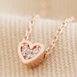 Tiny Crystal Heart Pendant Necklace in Rose Gold on Beige Fabric