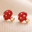 Red Enamel Mushroom Stud Earrings in Gold on Neutral Fabric
