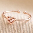 Adjustable Crystal Heart Ring in Rose Gold on Beige Fabric