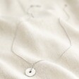 Spinning Disc Pendant Necklace in Platinum on Neutral Coloured Fabric Showing Full Length