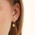 Close Up of Model Wearing Sunburst Charm Huggie Hoop Earring in Gold