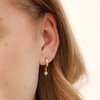 Close Up of Model Wearing Tiny Star Charm Huggie Hoop Earrings in Gold