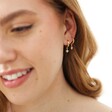 Model Wears Tiny Star Charm Huggie Hoop Earrings in Gold Layered Together in Same Ear