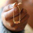 Model Holding Triple Enamel Flower Pendant Necklace in Gold