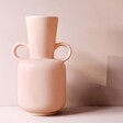 Empty Pink Ceramic Vase with Handles Against Pink Background