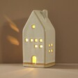 Rustic Ceramic House LED Decoration in Dark Room against Neutral Background