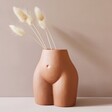 Small Porcelain Body Vase with bunny tails on beige background