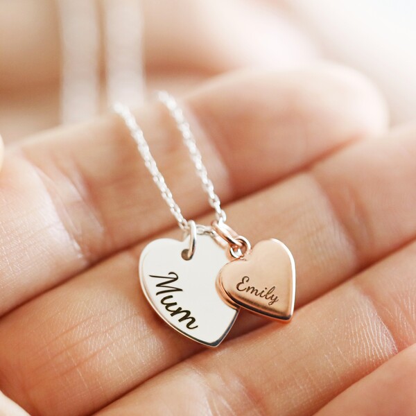 Personalised double heart charm necklace held in the hand of model with Mum and Emily engravings