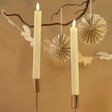 Set of 2 Cream LED Candles Close Up Against Decorative Background