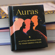 Front Cover of Auras: An Introduction to Energy Fields Book Leaning Against Stack of Books