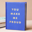 Front Cover of You Make Me Proud Book Standing in Front of Pile of Books